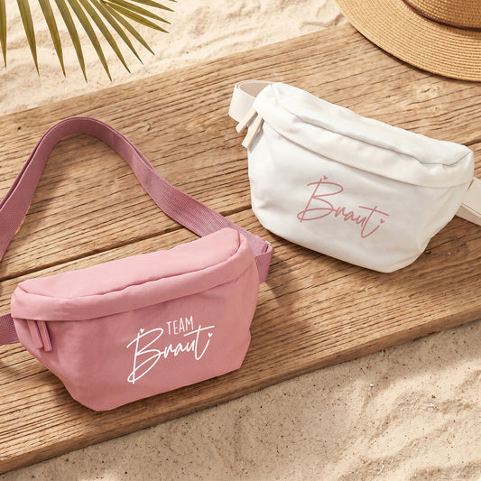 JGA Bauchtaschen für Braut und Team Braut in Rosa und Creme auf Holzuntergrund mit sommerlicher Dekoration
