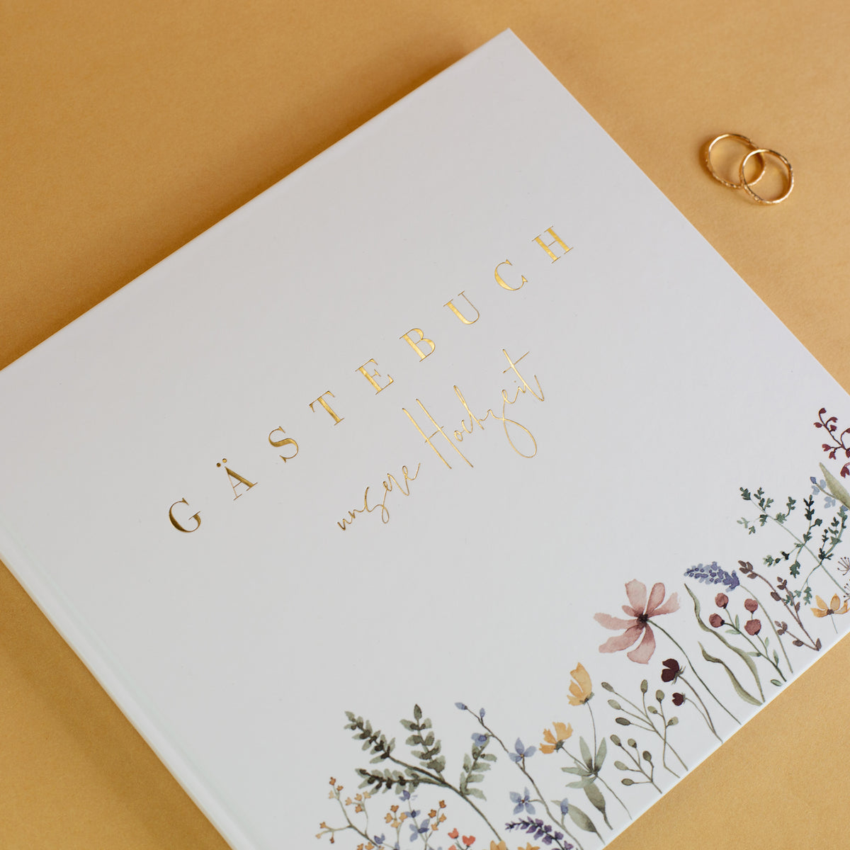 Gästebuch Hochzeit mit Goldprägung und floralem Design – Hardcover in Weiß mit Eheringen als Dekoration