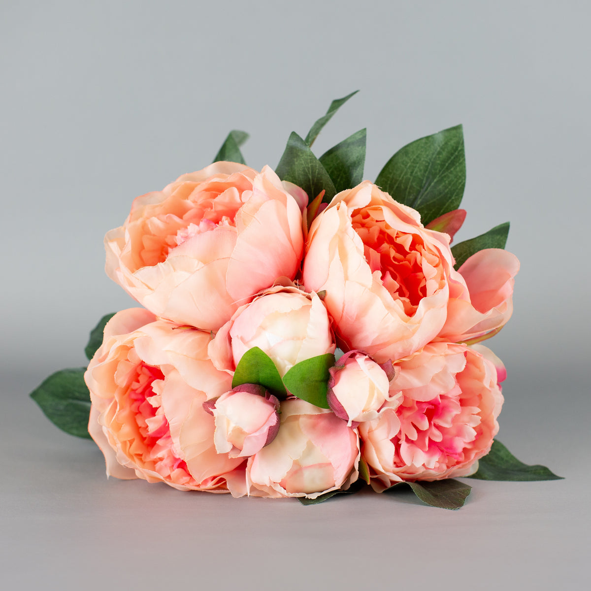 Kunstblumenstrauß mit rosa Pfingstrosen und grünen Blättern – frontal arrangiert