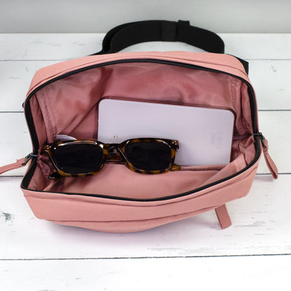 Geöffnete altrosa Bauchtasche mit Innenfach, Smartphone und Sonnenbrille