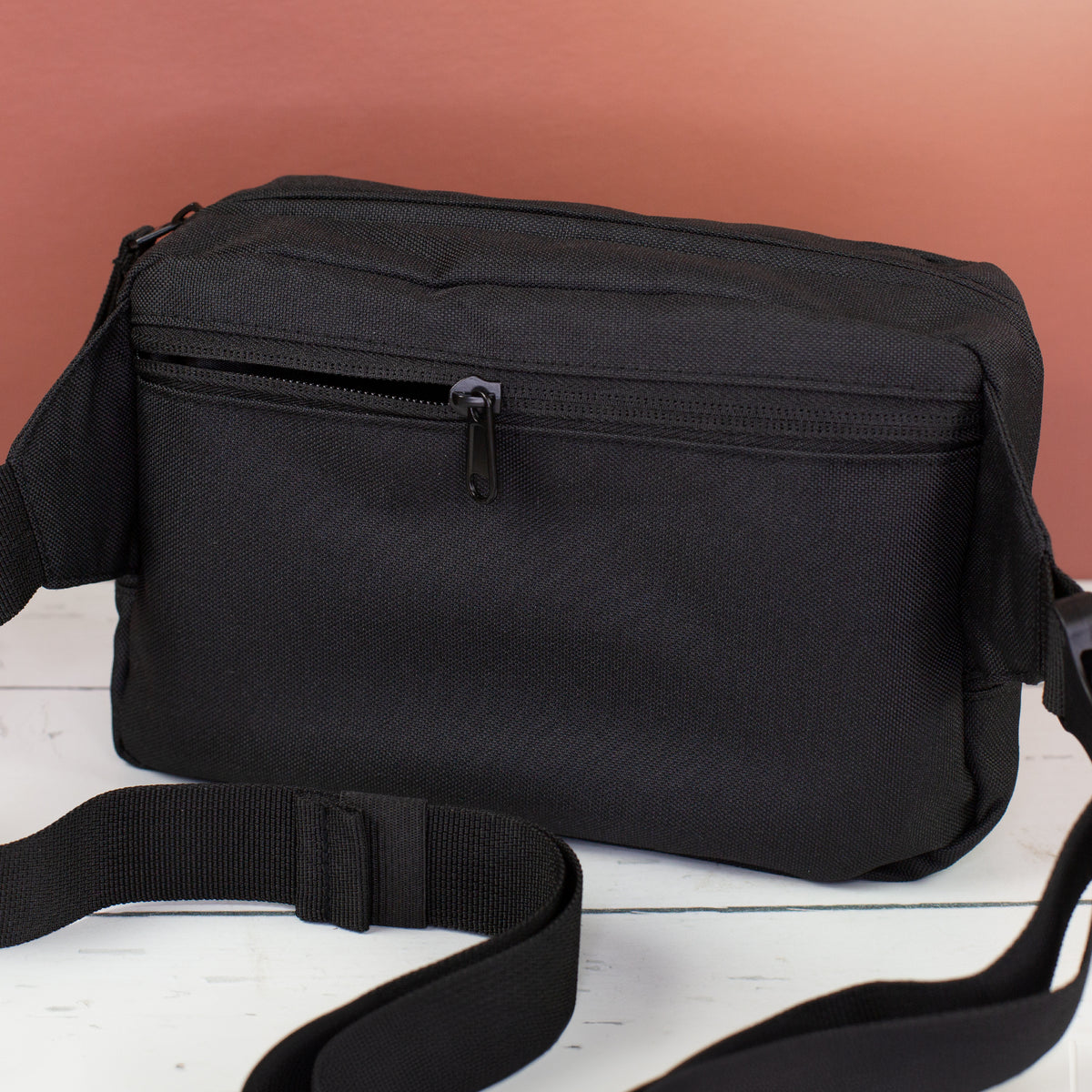 Rückseite der schwarzen Bauchtasche mit Reißverschlussfach und verstellbarem Gurt