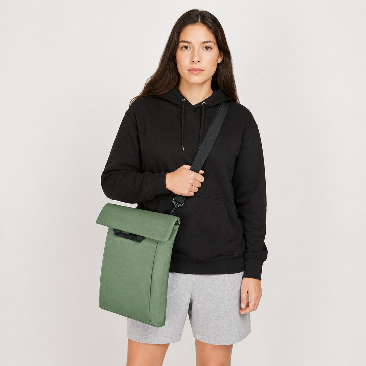 Model trägt den jadegrünen 2-in-1 Rucksack als Umhängetasche und zeigt die alternative Tragevariante des Produkts
