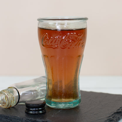 Gefülltes Coca-Cola Schnapsglas auf Schieferplatte mit kleiner Flasche im Hintergrund