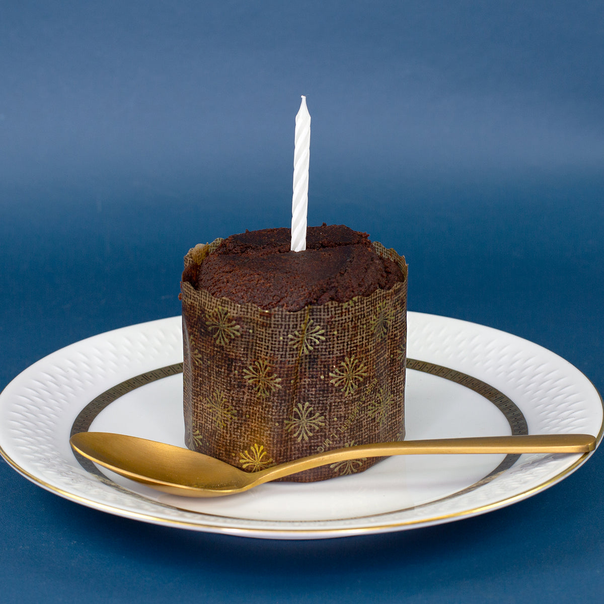 Schokoladen Brownie Kuchen mit weißer Geburtstagskerze auf Teller als Serviervorschlag