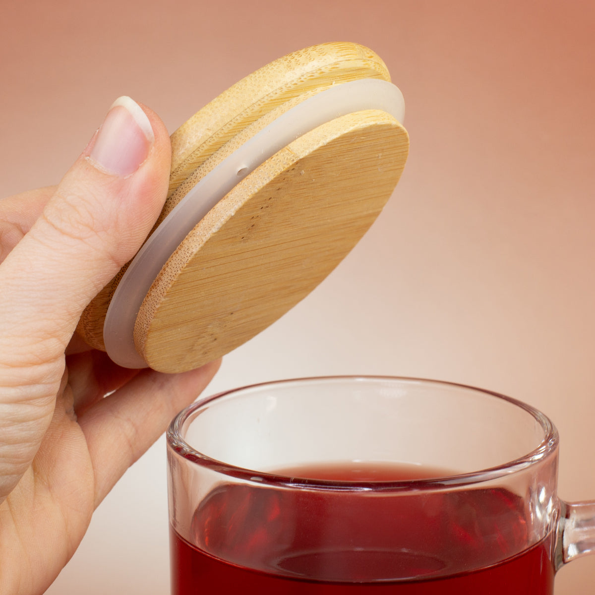 Bambusdeckel wird von Hand vom personalisierten Teeglas abgenommen