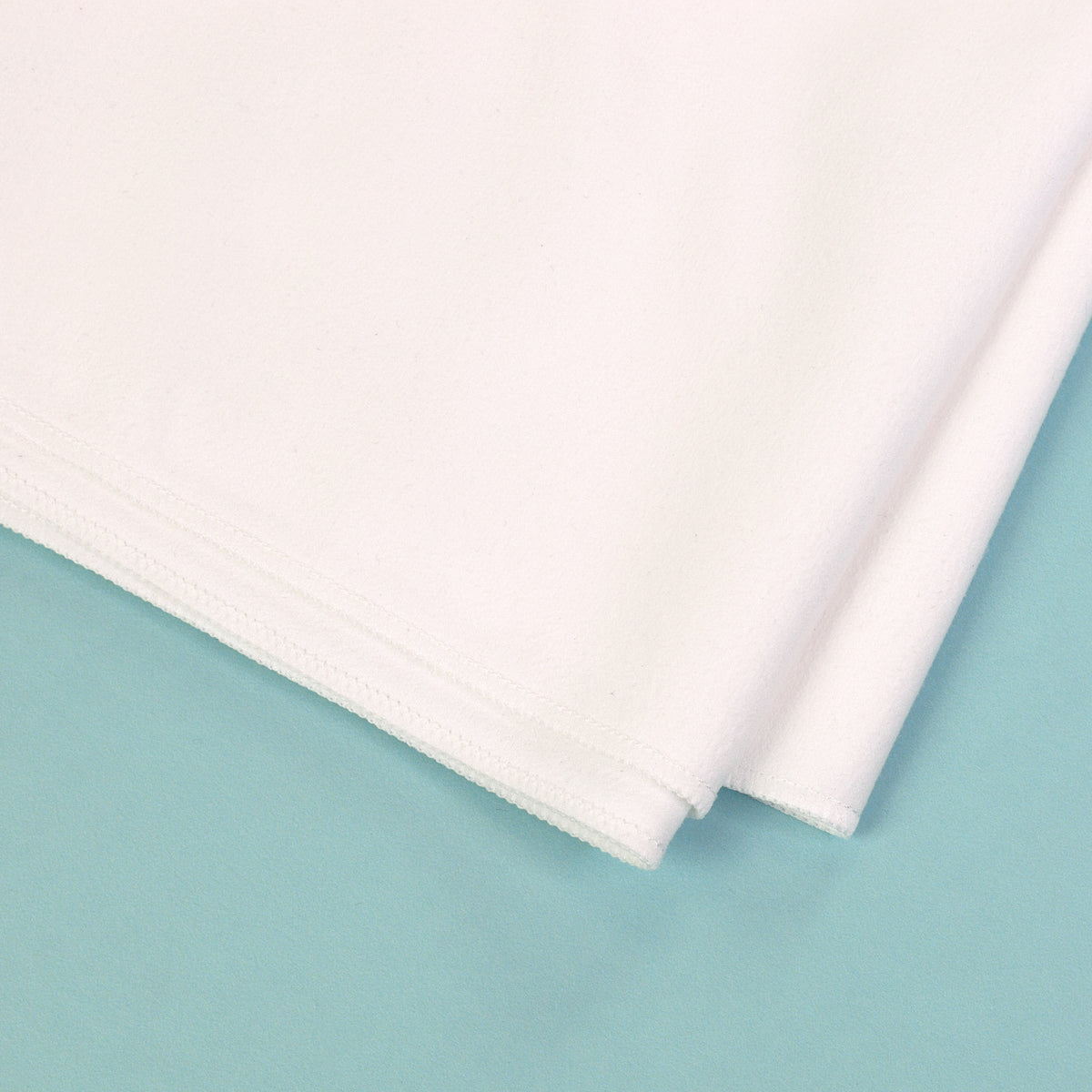 Detailaufnahme von Material und Naht eines weißen schnelltrocknenden Sporthandtuchs