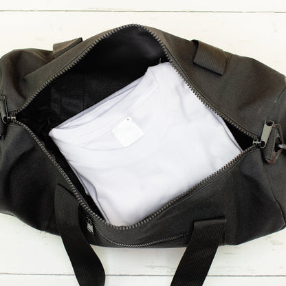 Schwarze Reisetasche mit Kleidung im Hauptfach als kleine Tasche für unterwegs