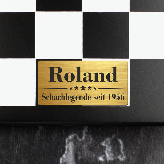 Nahaufnahme der goldfarbenen Metallplakette mit Gravur Roland Schachlegende seit 1956 auf dem Schachbrett