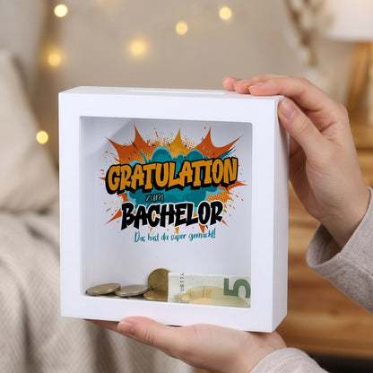 Bilderrahmen-Spardose „Gratulation zum Bachelor“ mit Geldschein und Münzen hinter Glas
