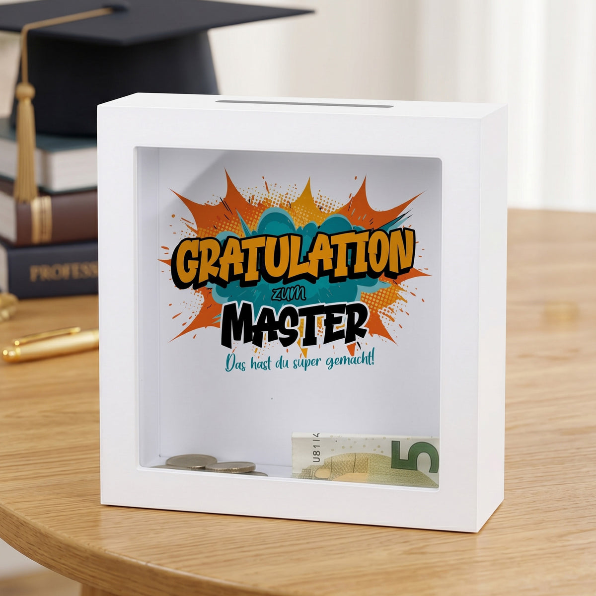 Geldgeschenk-Spardose „Gratulation zum Master“ im weißen Bilderrahmen auf festlicher Deko