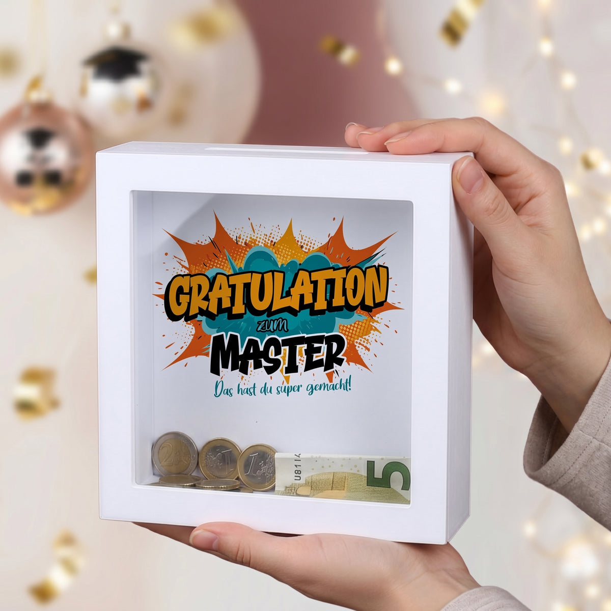 Geldgeschenk-Spardose „Gratulation zum Master“ im weißen Bilderrahmen auf festlicher Deko