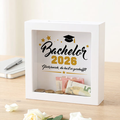 Bilderrahmen-Spardose „Bachelor 2026“ mit Geldschein und Münzen hinter Glas