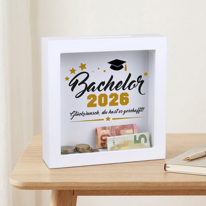 Bilderrahmen-Spardose „Bachelor 2026“ mit Geldschein und Münzen hinter Glas