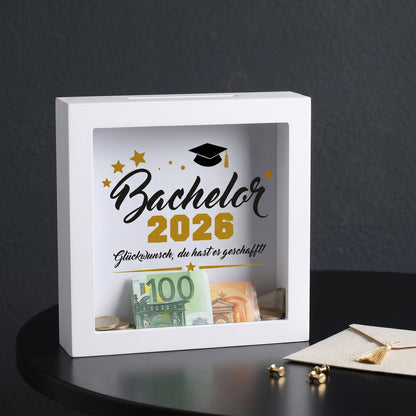 Bilderrahmen-Spardose „Bachelor 2026“ mit Geldschein und Münzen hinter Glas