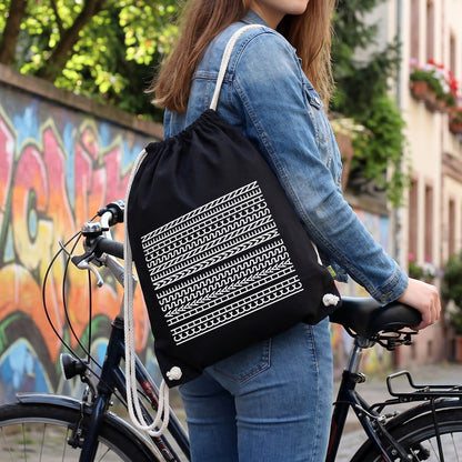 Schwarzer Turnbeutel mit versteckter Botschaft und weißem Aufdruck als Rucksack beim Fahrradfahren