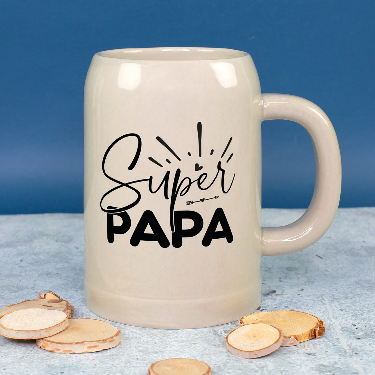 Kleiner Bierkrug „Super Papa“ vor blauem Hintergrund mit Holzdeko