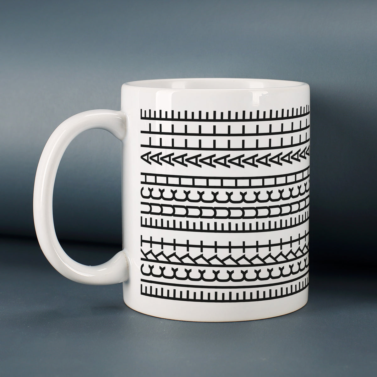 Weiße Tasse mit modernem Musterdesign vor dunklem Hintergrund