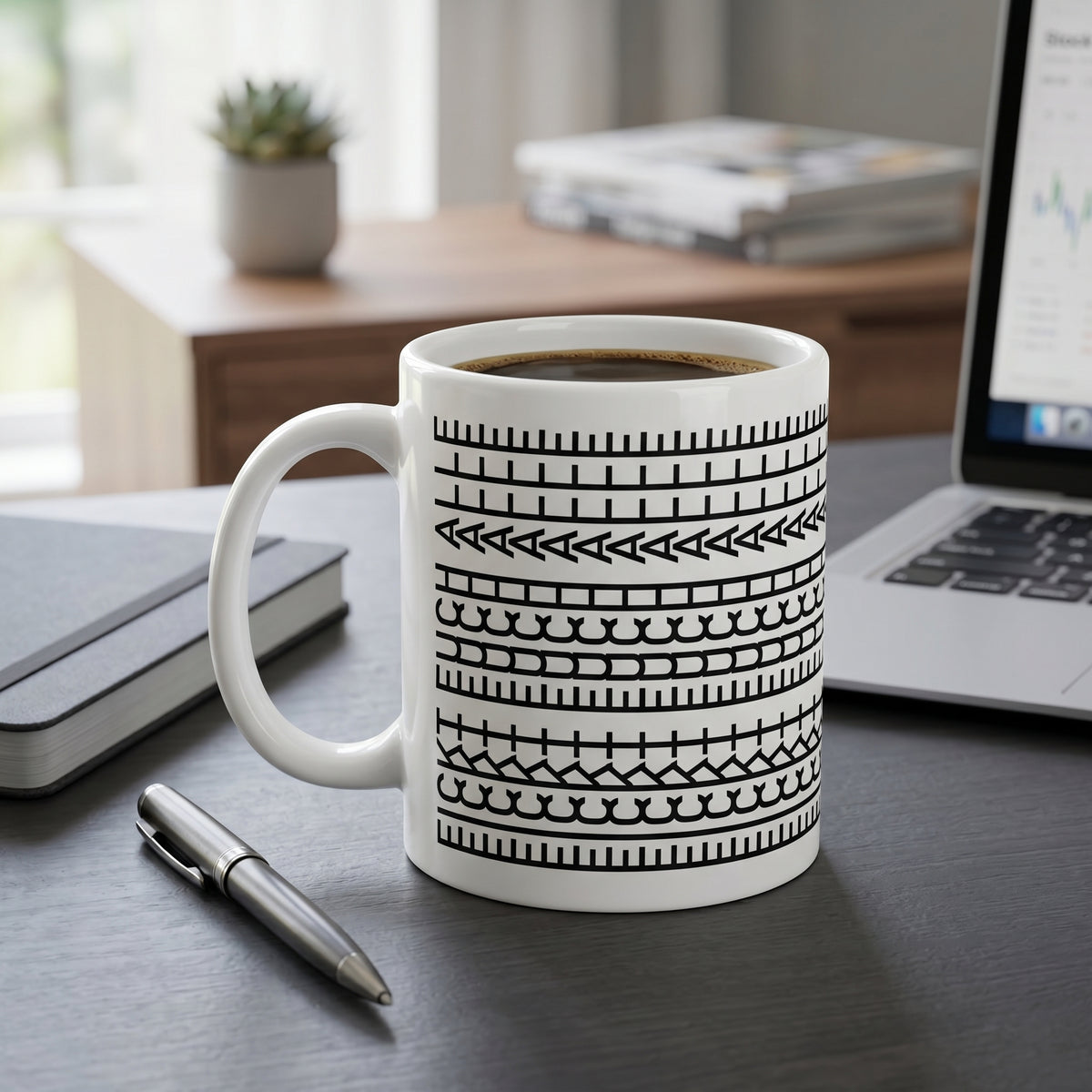 Lustige Tasse mit modernem Schwarz-Weiß-Muster auf Schreibtisch neben Laptop und Notizbuch