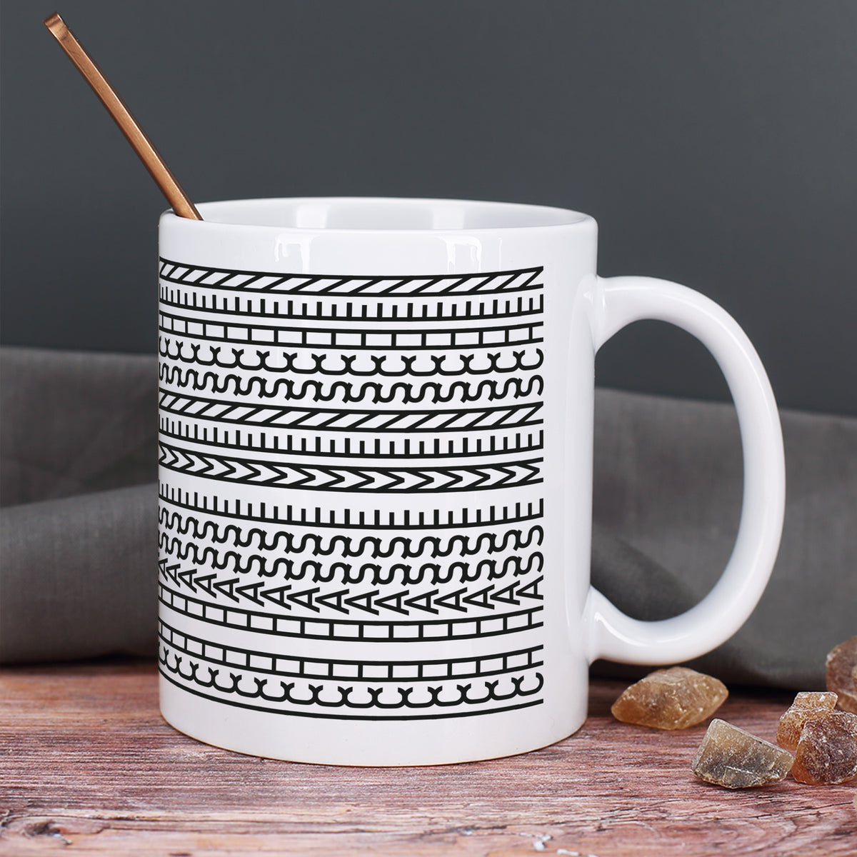Keramiktasse mit Schwarz-Weiß-Muster und Löffel auf Holztisch mit dunklem Hintergrund