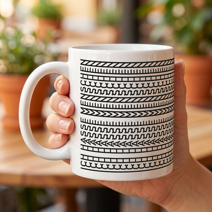 Keramiktasse mit grafischem Schwarz-Weiß-Muster wird in der Hand gehalten