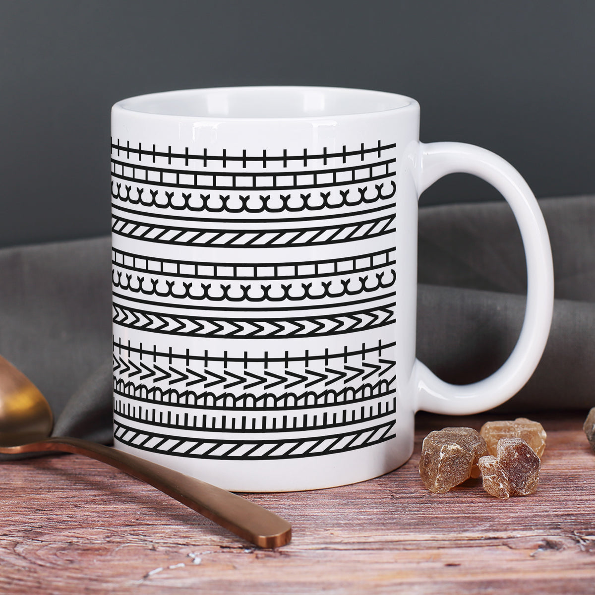 Keramiktasse mit modernem Muster auf rustikalem Holztisch neben einem Löffel