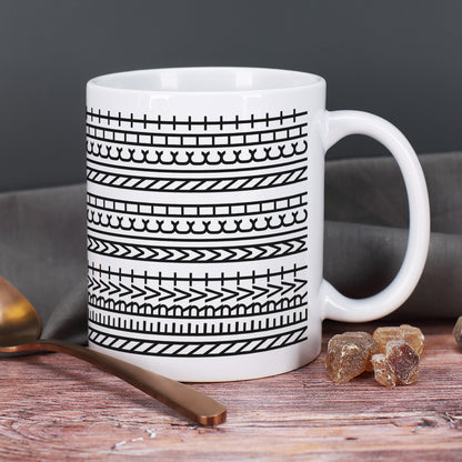 Keramiktasse mit modernem Muster auf rustikalem Holztisch neben einem Löffel