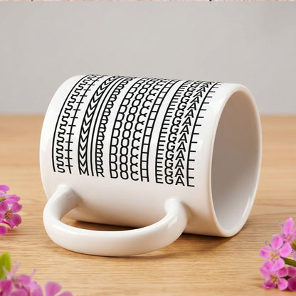 Seitlich liegende Tasse mit verstecktem Schriftzug „IST MIR DOCH EGAL“ auf Holztisch