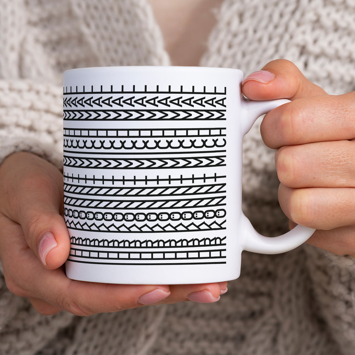 Lustige Tasse mit Schwarz-Weiß-Muster wird in beiden Händen gehalten