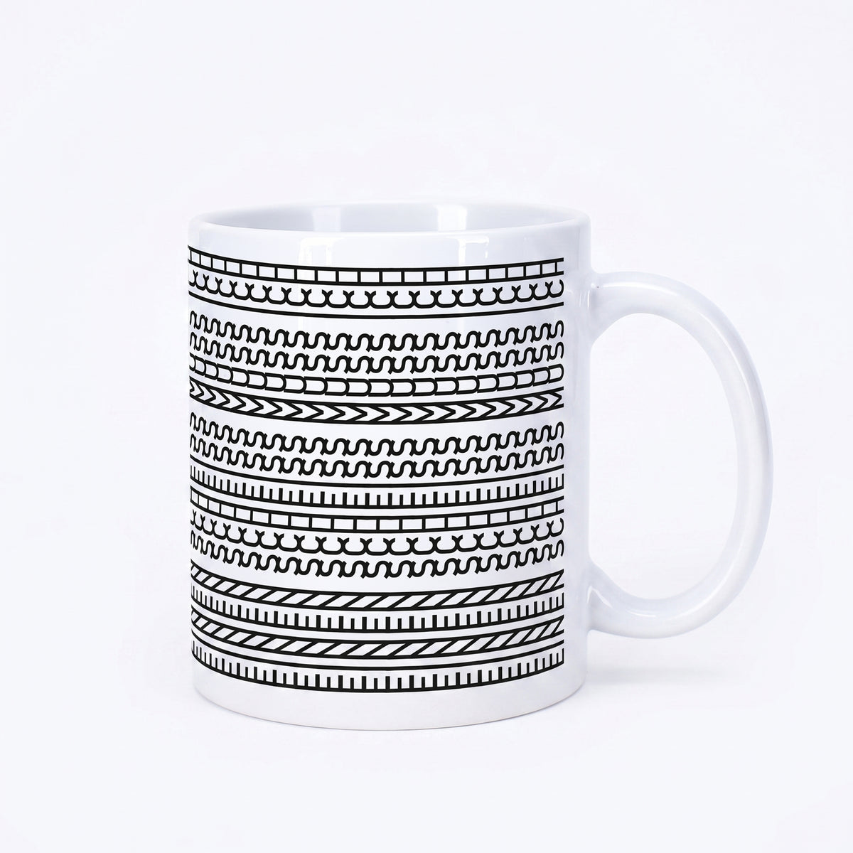 Weiße Kaffeetasse mit schwarzem grafischem Muster und versteckter Botschaft „Einen Scheiss muss ich“