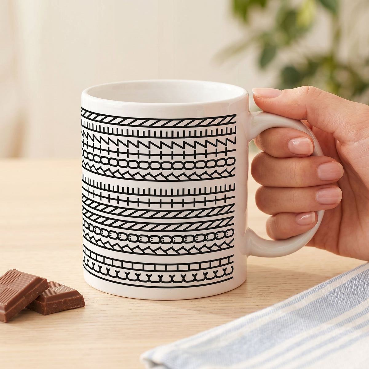 Weiße Kaffeetasse mit schwarzem Muster und versteckter Botschaft „Ich könnte kotzen“ in der Hand
