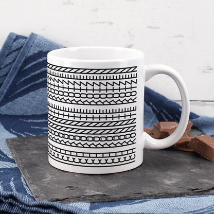 Weiße Keramiktasse mit versteckter Botschaft im Muster, dekoriert mit Schokolade und blauem Tuch