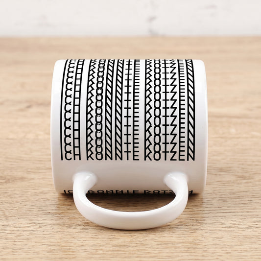Liegende Kaffeetasse mit sichtbarer versteckter Botschaft „Ich könnte kotzen“ im Schwarz-Weiß-Muster