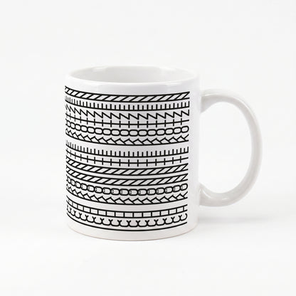 Kaffeetasse mit schwarzem Muster und versteckter Botschaft „Ich könnte kotzen“ auf weißem Hintergrund