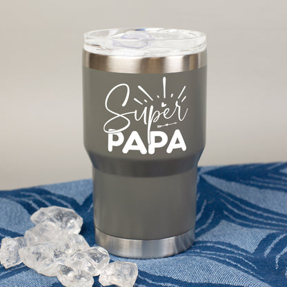 Grauer Thermobecher mit Super Papa Motiv auf blauem Tuch neben Eiswürfeln