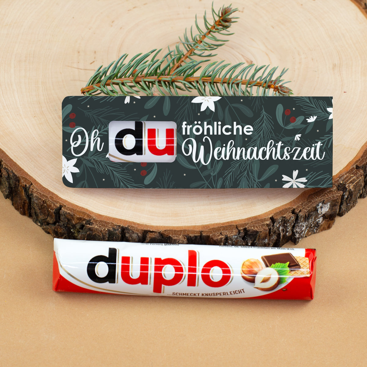duplo Riegel „Oh du fröhliche Weihnachtszeit“ mit dunkelgrünem Weihnachtsmotiv und Tannenzweigen