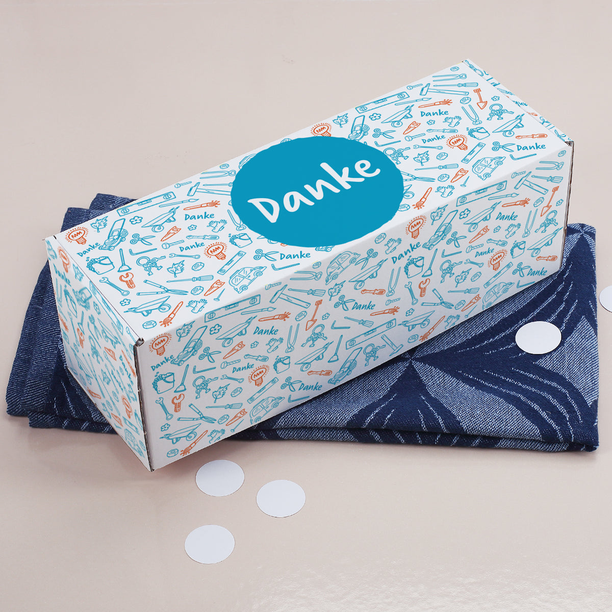 Geschenkverpackung mit Werkzeug-Motiv und großem blauen Danke-Kreis von schräg oben fotografiert