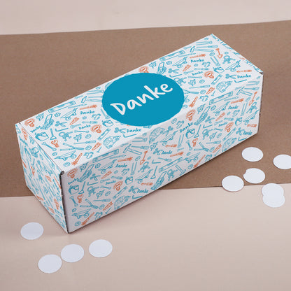 Bunte Danke-Box mit Werkzeug-Illustrationen auf Stoffunterlage und runden Konfetti-Punkten