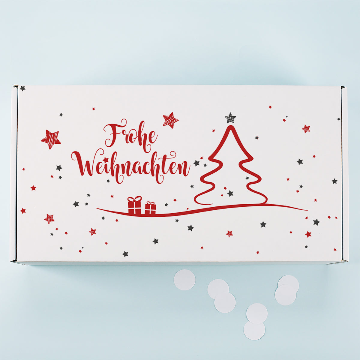 Weiße Geschenkbox von oben mit rotem Weihnachtsbaum Motiv, Geschenken, Sternen und Frohe Weihnachten Schriftzug