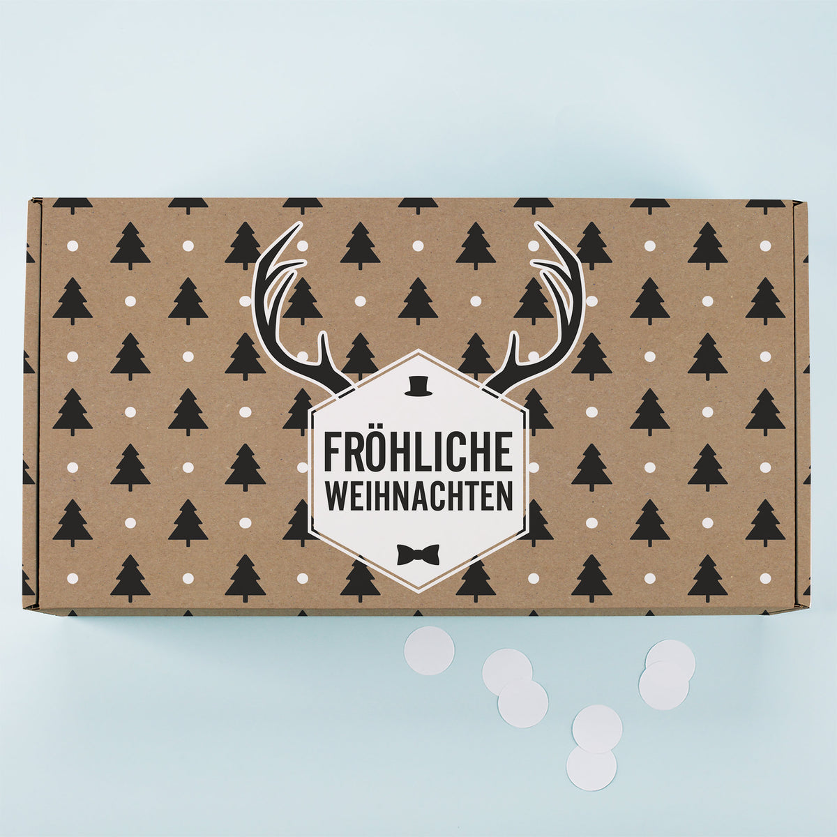 Kraftpapier Geschenkbox von oben mit Tannenbaum Muster, weißen Punkten, Rentier Motiv und Fröhliche Weihnachten Schriftzug