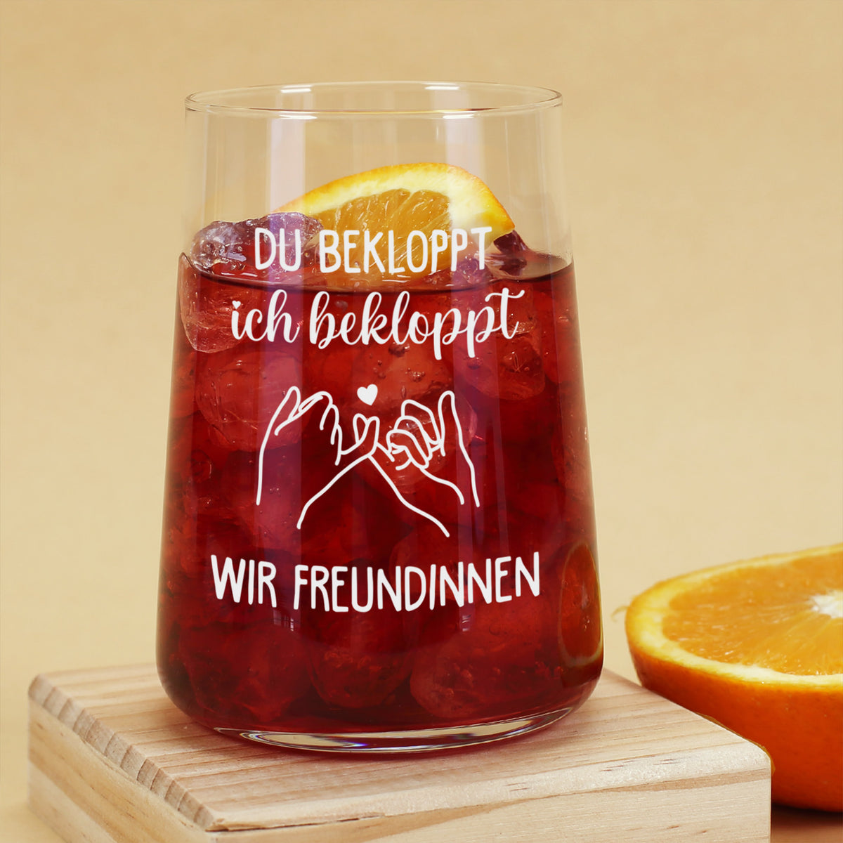 Trinkglas mit rotem Getränk, Eiswürfeln, Orangenscheibe und witzigem Spruch für Freundinnen