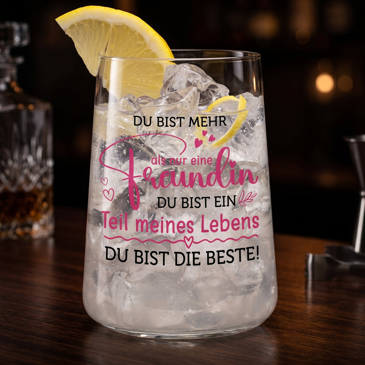 Trinkglas mit Freundinnen-Spruch und Zitronenscheibe, gefüllt mit Eiswürfeln in dunkler Bar-Optik