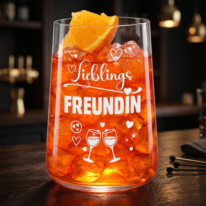 Trinkglas Lieblingsfreundin mit orangefarbenem Getränk, Eis und Orangenscheibe, stimmungsvoll auf dunklem Hintergrund fotografiert