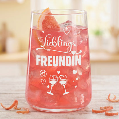 Trinkglas Lieblingsfreundin mit rosafarbenem Getränk, Eis und Grapefruitscheibe, freigestellt vor hellem Hintergrund