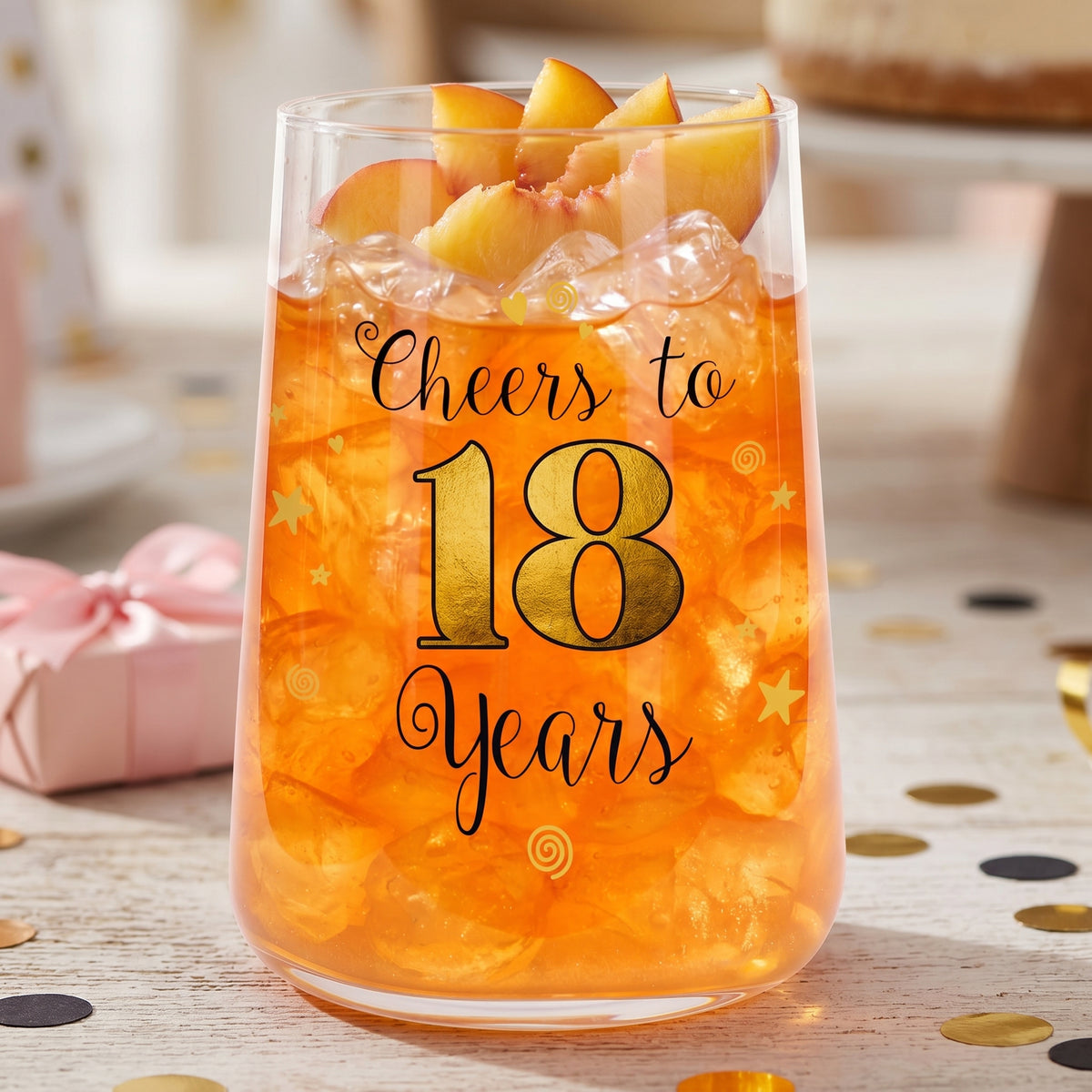 Geburtstagsglas zum 18. Geburtstag mit orangefarbenem Cocktail, Eiswürfeln und Obstgarnitur
