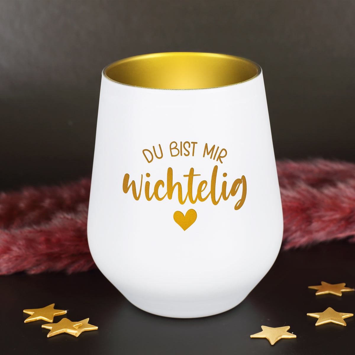 Weißes Windlicht mit goldener Innenbeschichtung und Wichtelig-Spruch auf dunklem Hintergrund