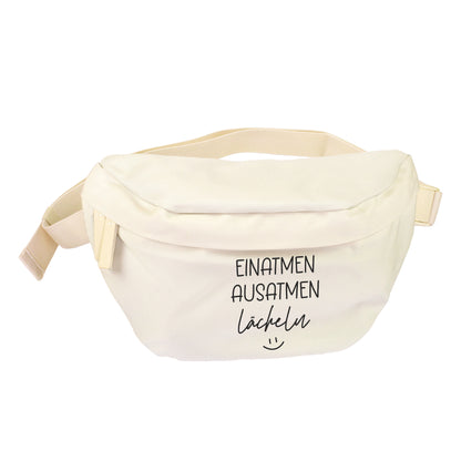 Cremefarbene Bauchtasche mit Spruch Einatmen Ausatmen Lächeln freigestellt auf weißem Hintergrund