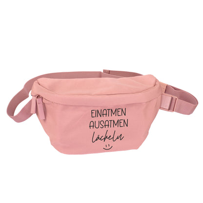 Rosafarbene Bauchtasche mit Spruch Einatmen Ausatmen Lächeln freigestellt auf weißem Hintergrund
