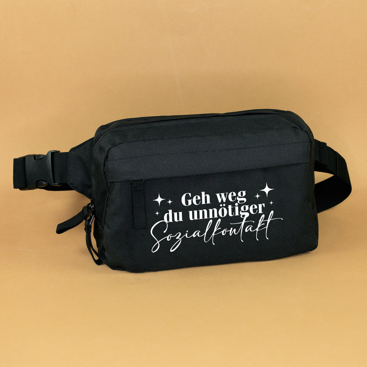 Schwarze Bauchtasche mit weißem Spruch Geh weg du unnötiger Sozialkontakt auf beigem Hintergrund