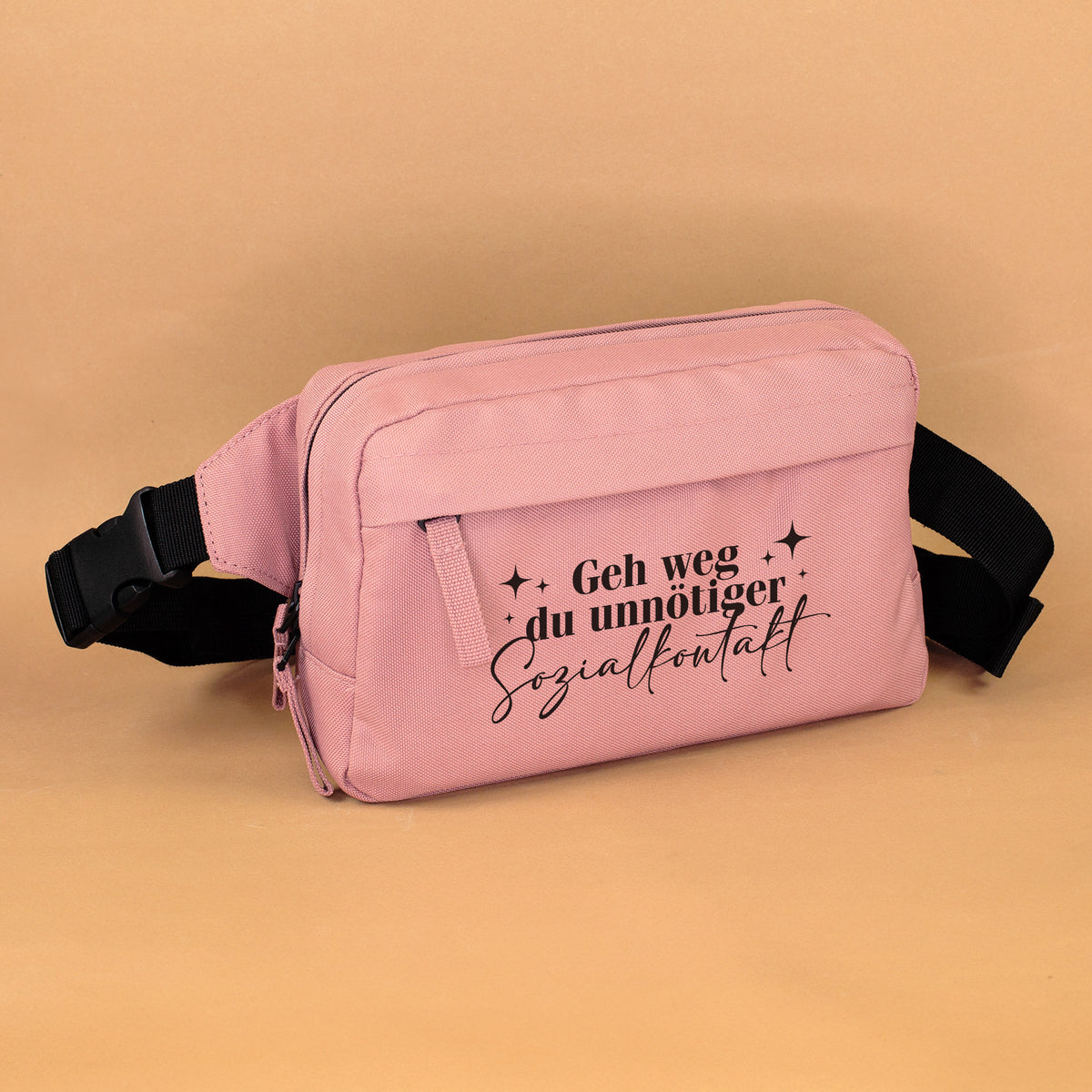 Altrosa Bauchtasche mit Spruch „Geh weg du unnötiger Sozialkontakt“ auf warmem Hintergrund