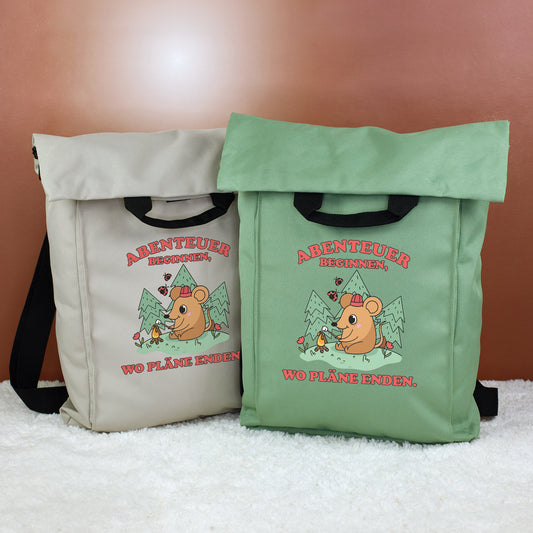 Zwei 2-in-1 Rucksäcke in Beige und Jadegrün mit Abenteuer-Maus Motiv und Spruch „Abenteuer beginnen, wo Pläne enden.“